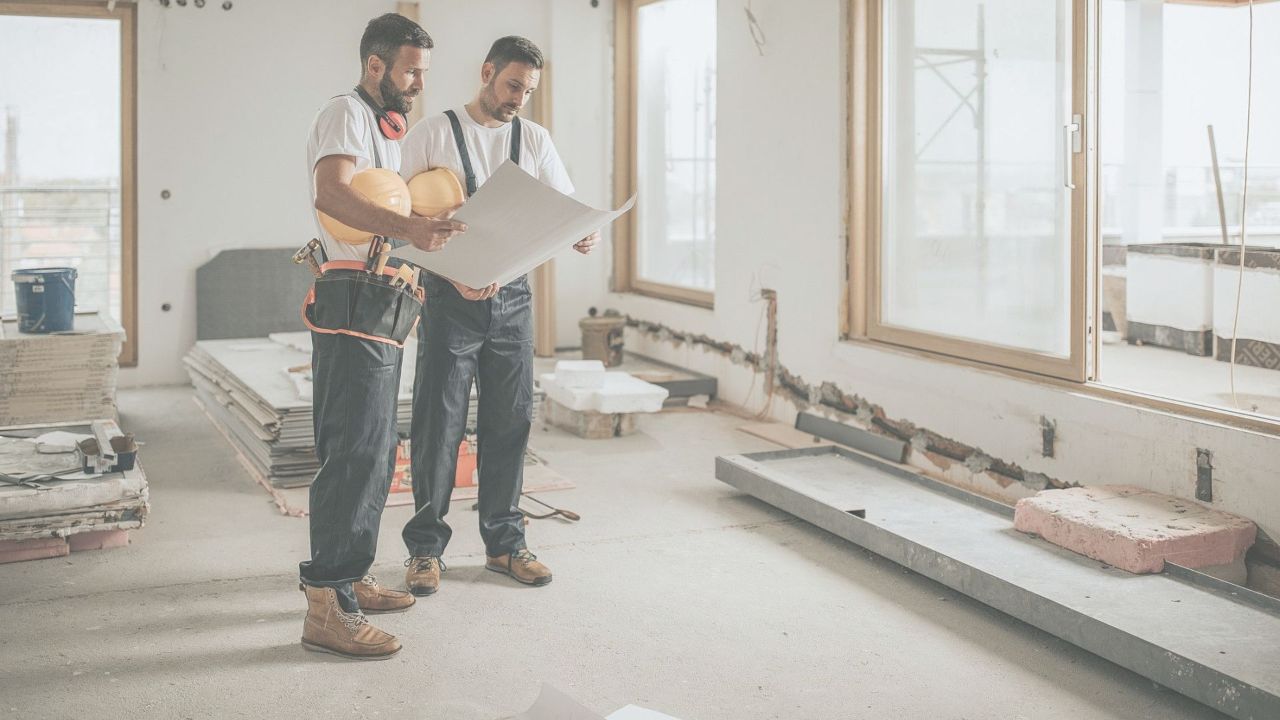 Dois engenheiros analisando a planta de um apartamento personalizado em construção