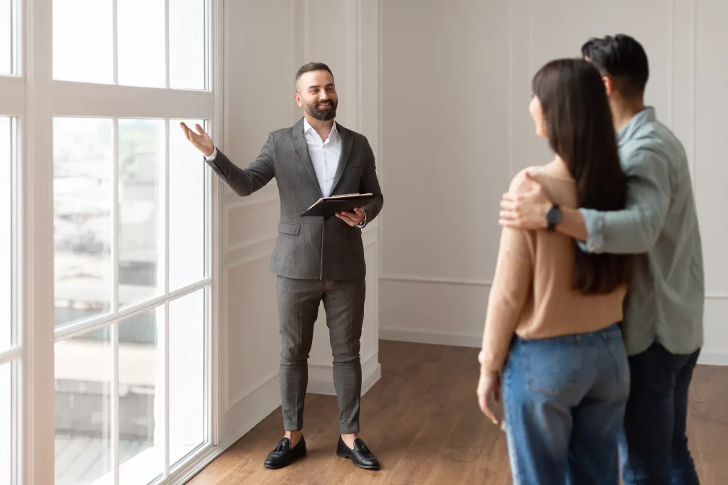 corretor de imóveis apresentando interior de apartamento para um casal